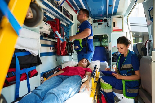 Healthcare professionals treating woman lying in hospital bed during medical examination